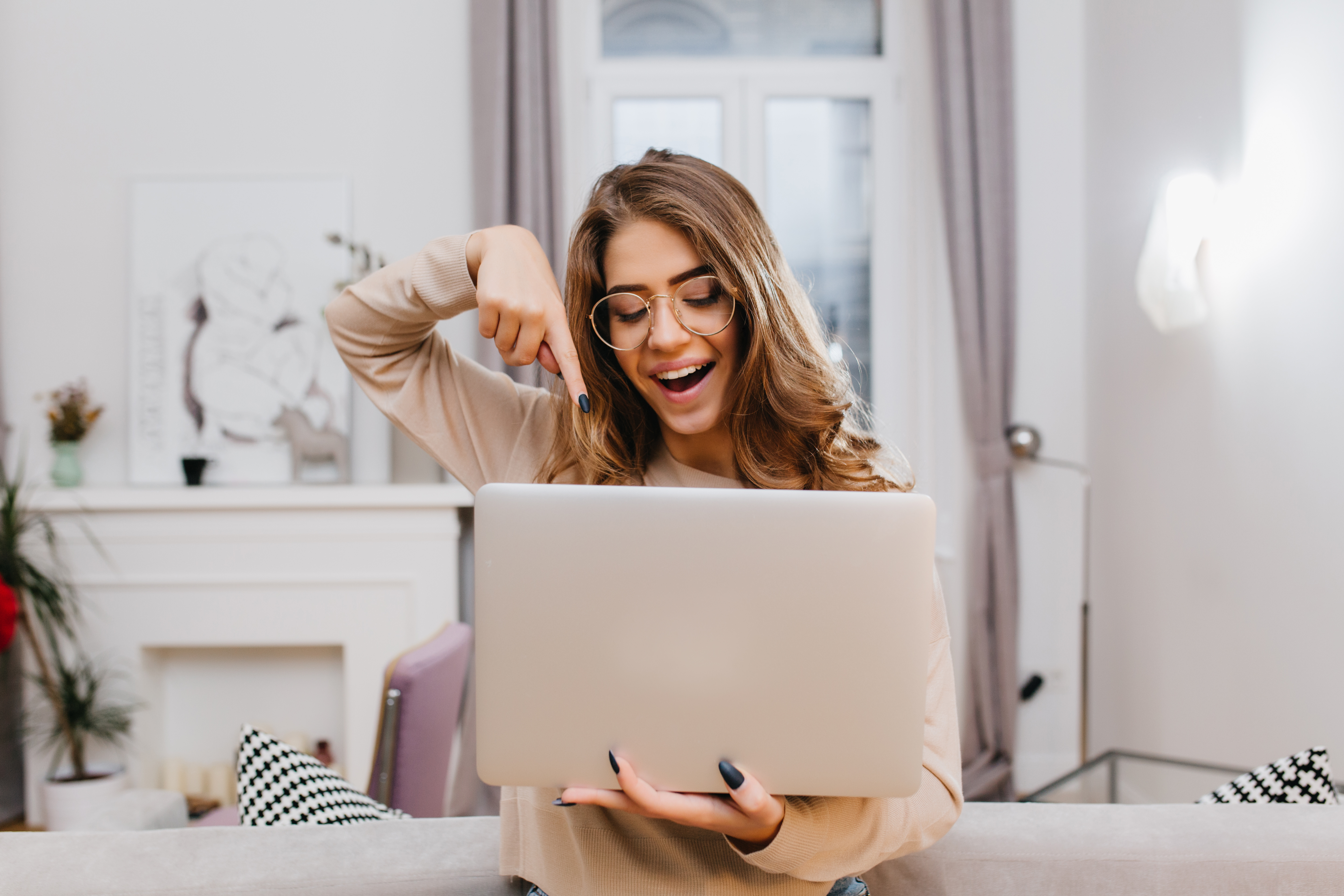 interested-girl-with-trendy-manicure-fooling-around-home-photoshoot-with-laptop