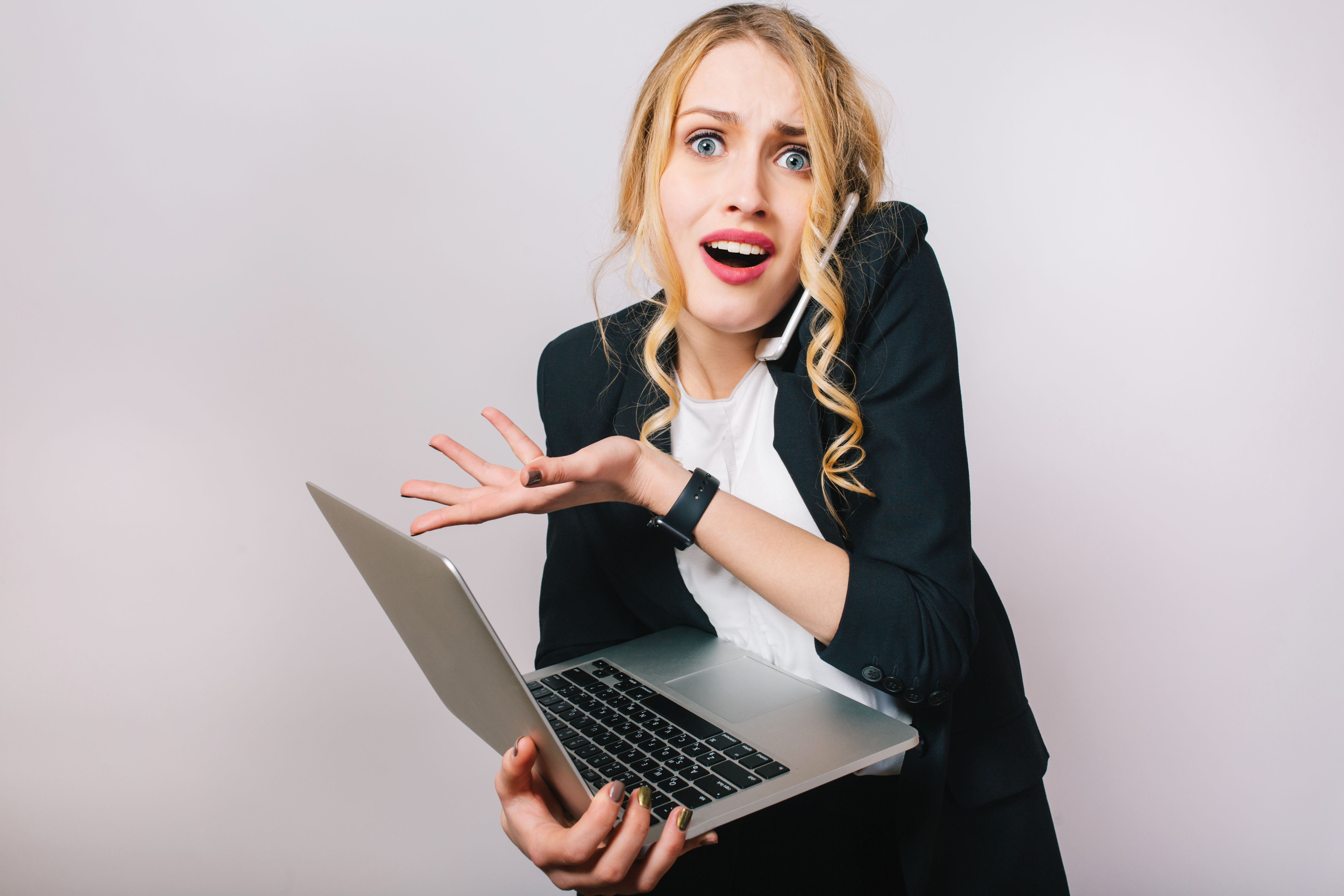 portrait-modern-funny-blonde-office-woman-white-shirt-black-jacket-working-with-laptop-being-busy-talking-phone-astonished-problems-expressing-true-emotions