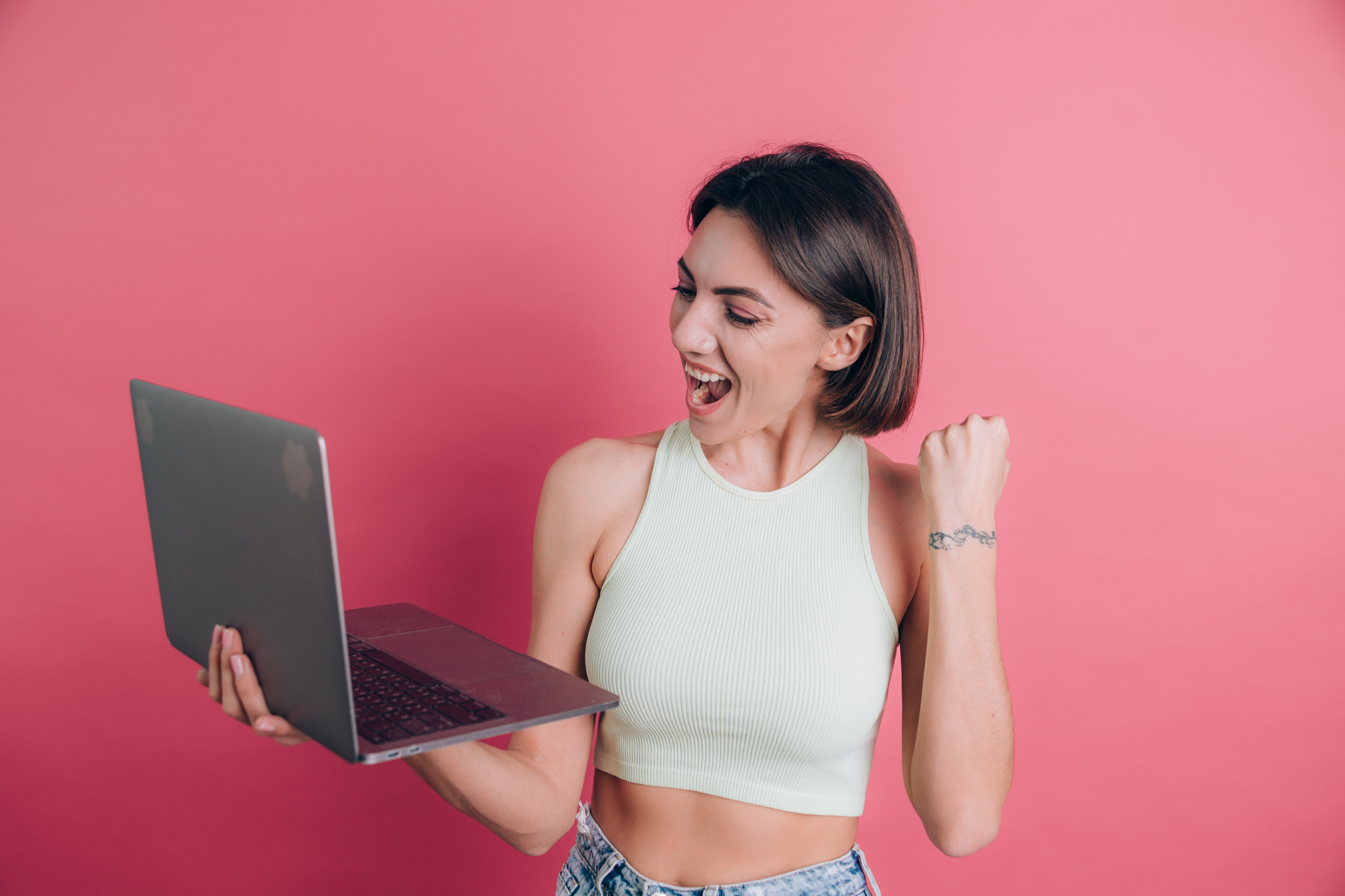 women-pink-background-winner-gesture-hold-laptop-computer