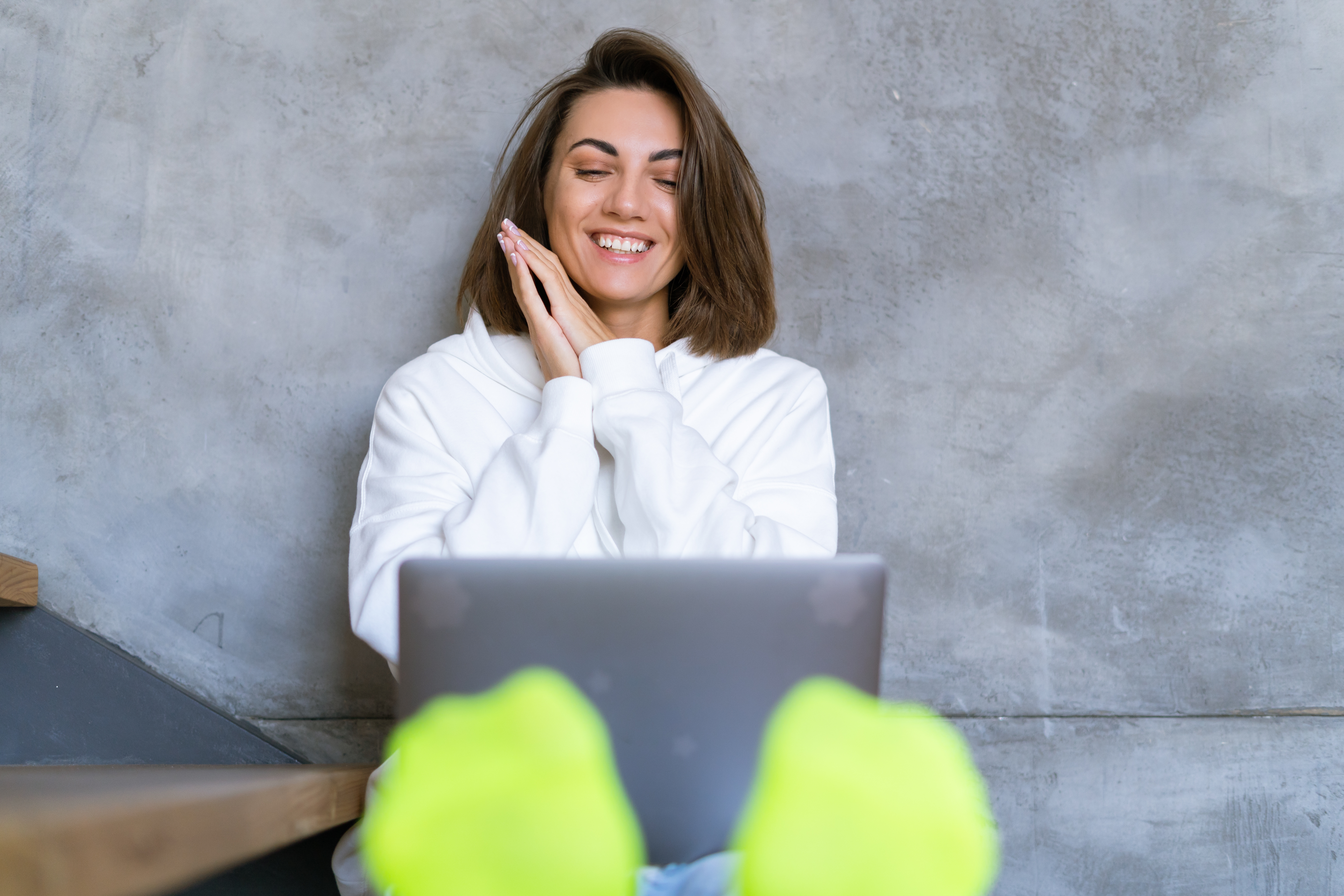 young-woman-home-white-hoodie-jeans-sits-stairs-with-laptop-her-knees